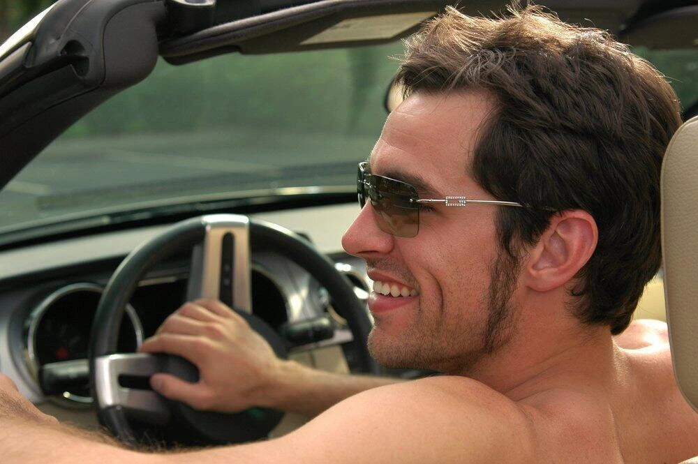 a person driving car shirtless